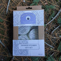 Shower steamer gift set packaging on a natural background with pine needles and branches.