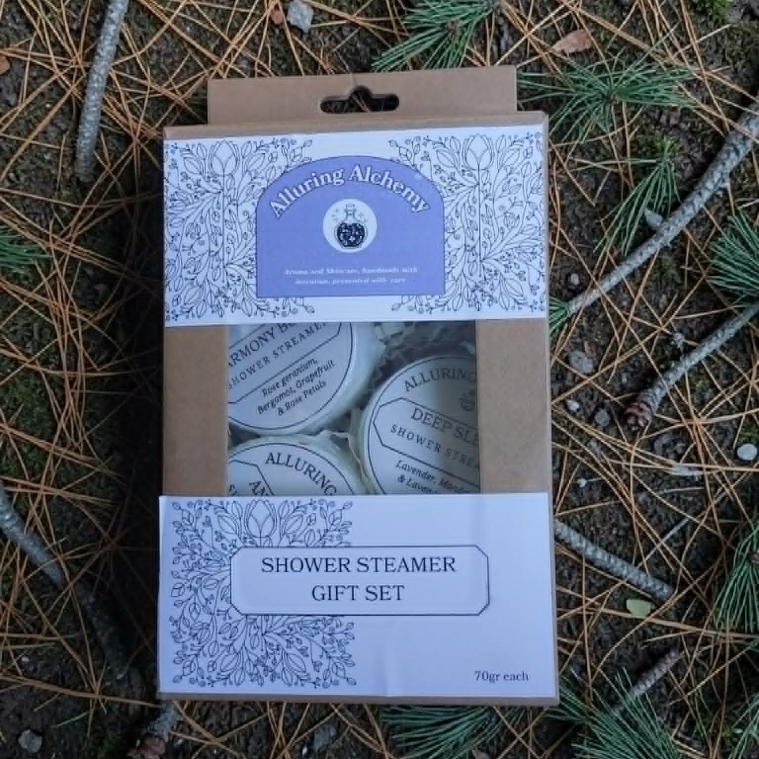 Shower steamer gift set packaging on a natural background with pine needles and branches.