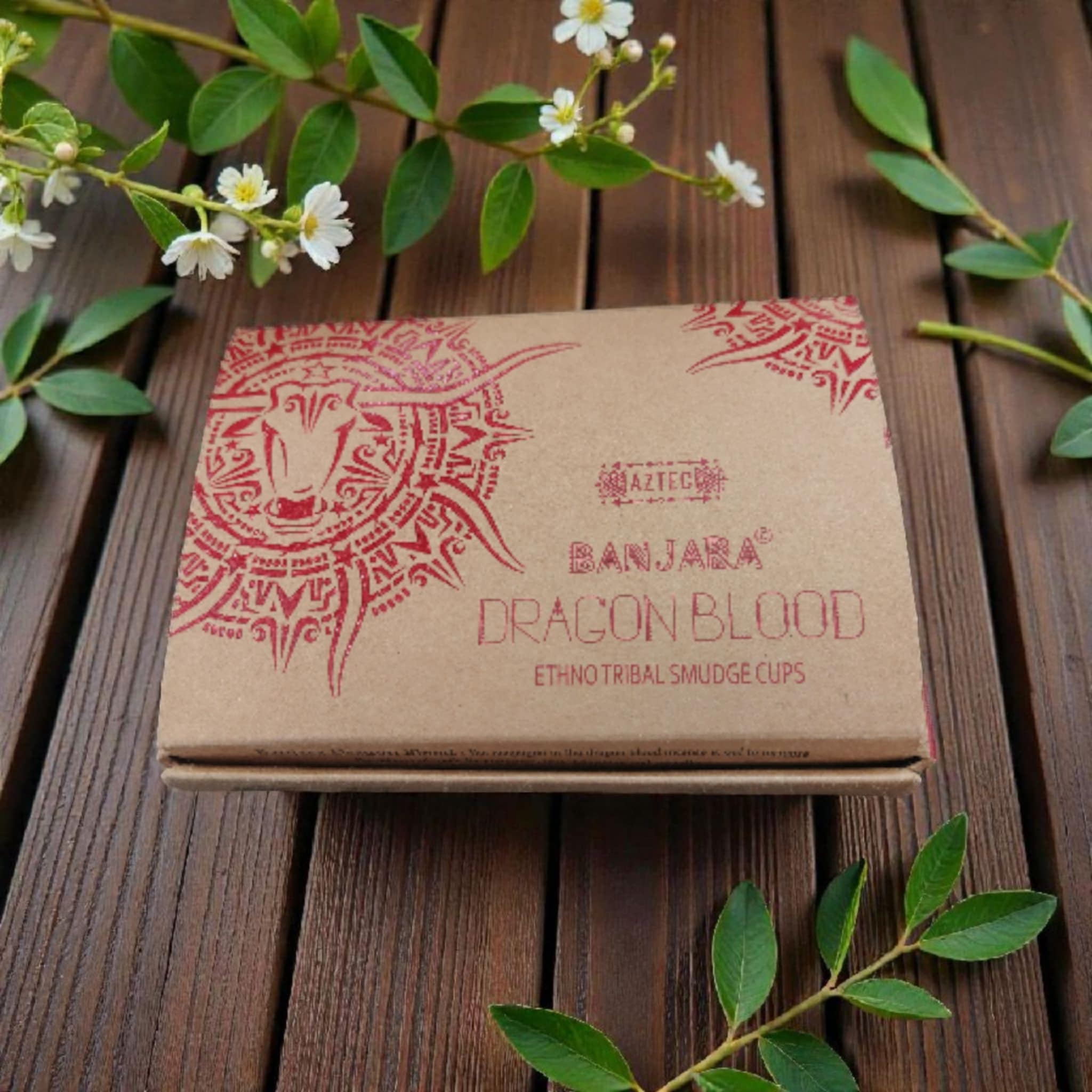 Brown packaging with red design and text on a wooden surface with green leaves and flowers.