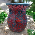 Decorative vase with red and black mosaic pattern on a natural background
