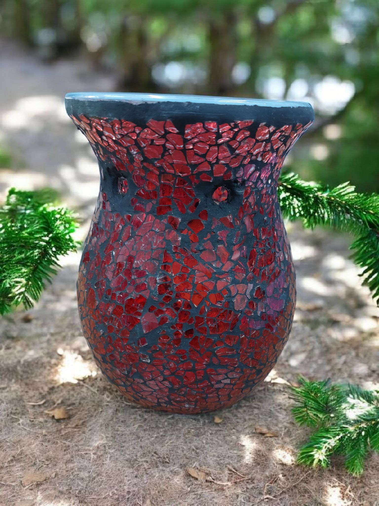 Decorative vase with red and black mosaic pattern on a natural background