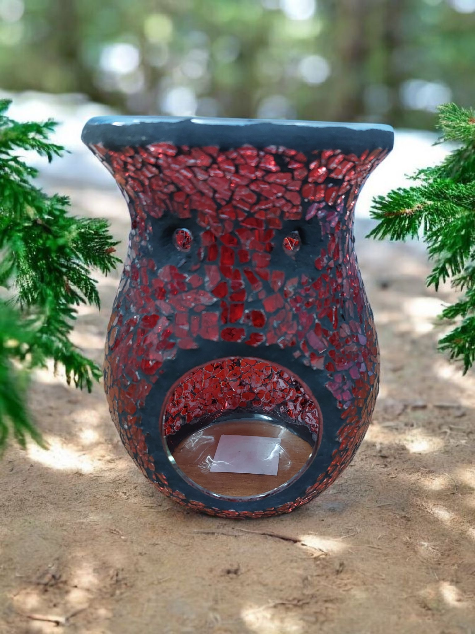 Decorative candle holder with red mosaic pattern on a natural background