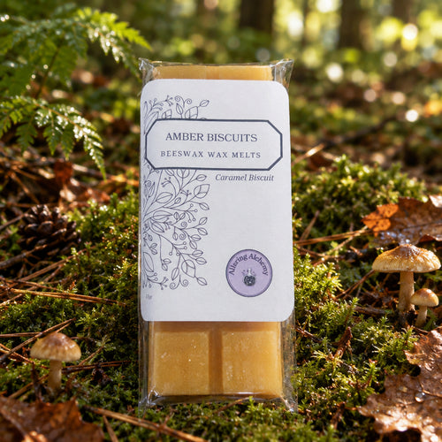 A packaged bar of amber biscuit beefwax melts in clear plastic wrapping with a white label, placed on a light wood surface.