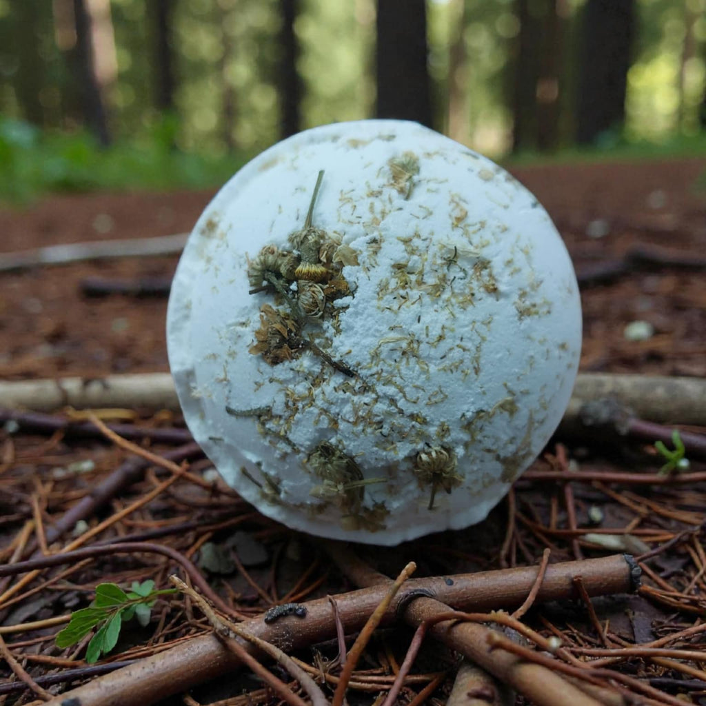 White bath bomb with chamomile petals on a forest floor