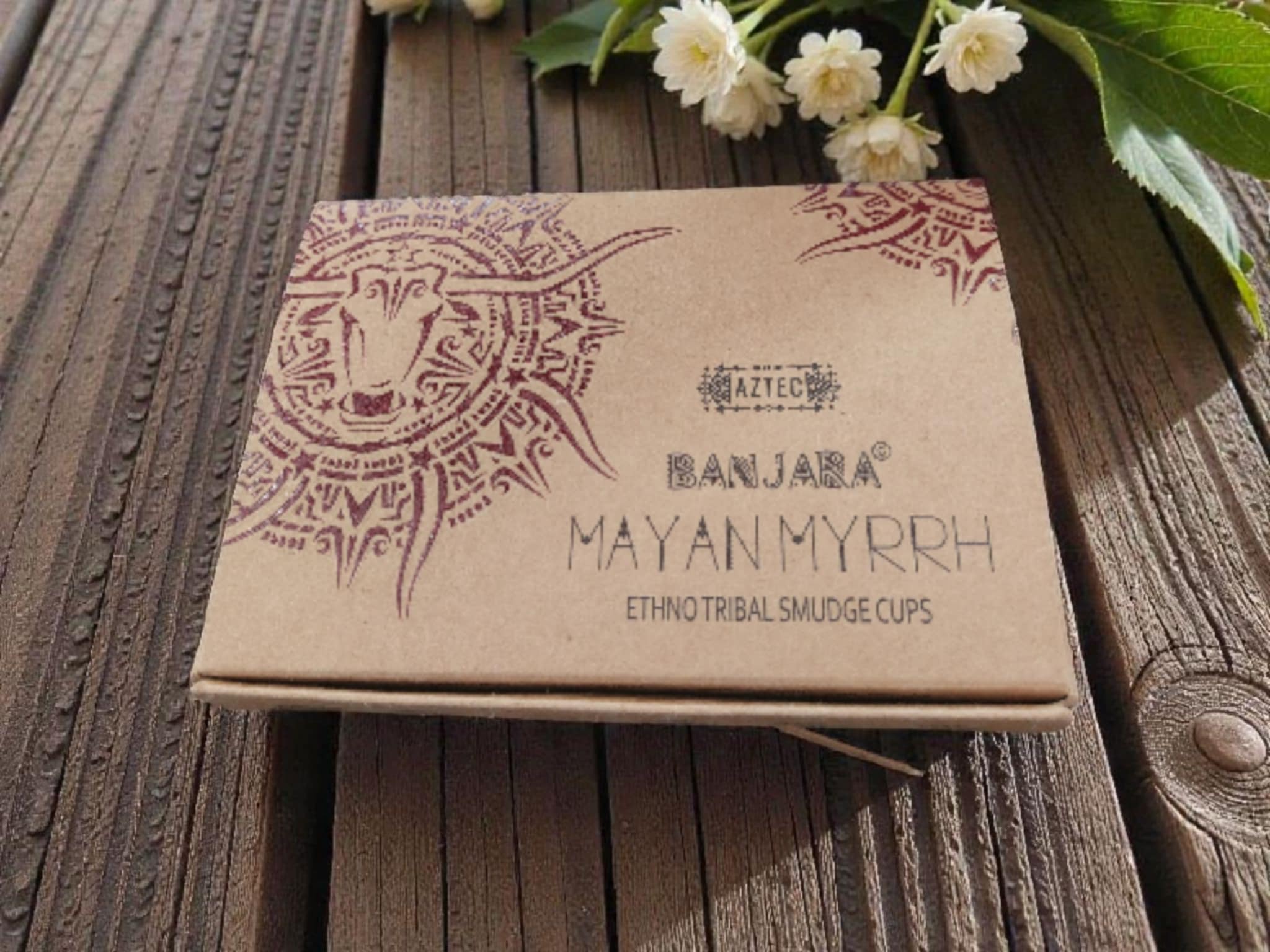 Banjara Mayan Myrrh packaging on a wooden surface with flowers.