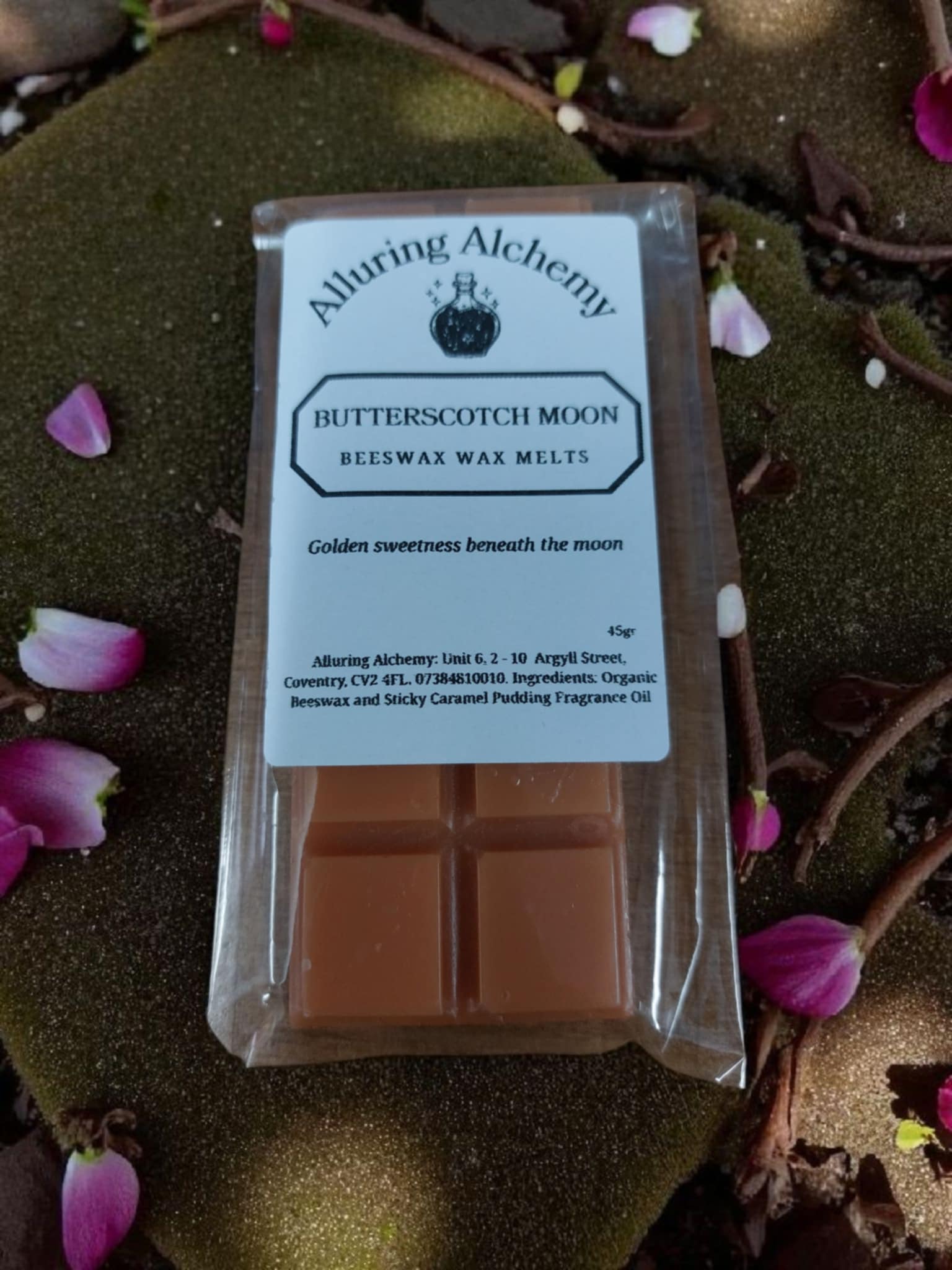 Packaged butterscotch moon beeswax wax melts with Alluring Alchemy branding on a decorative background.