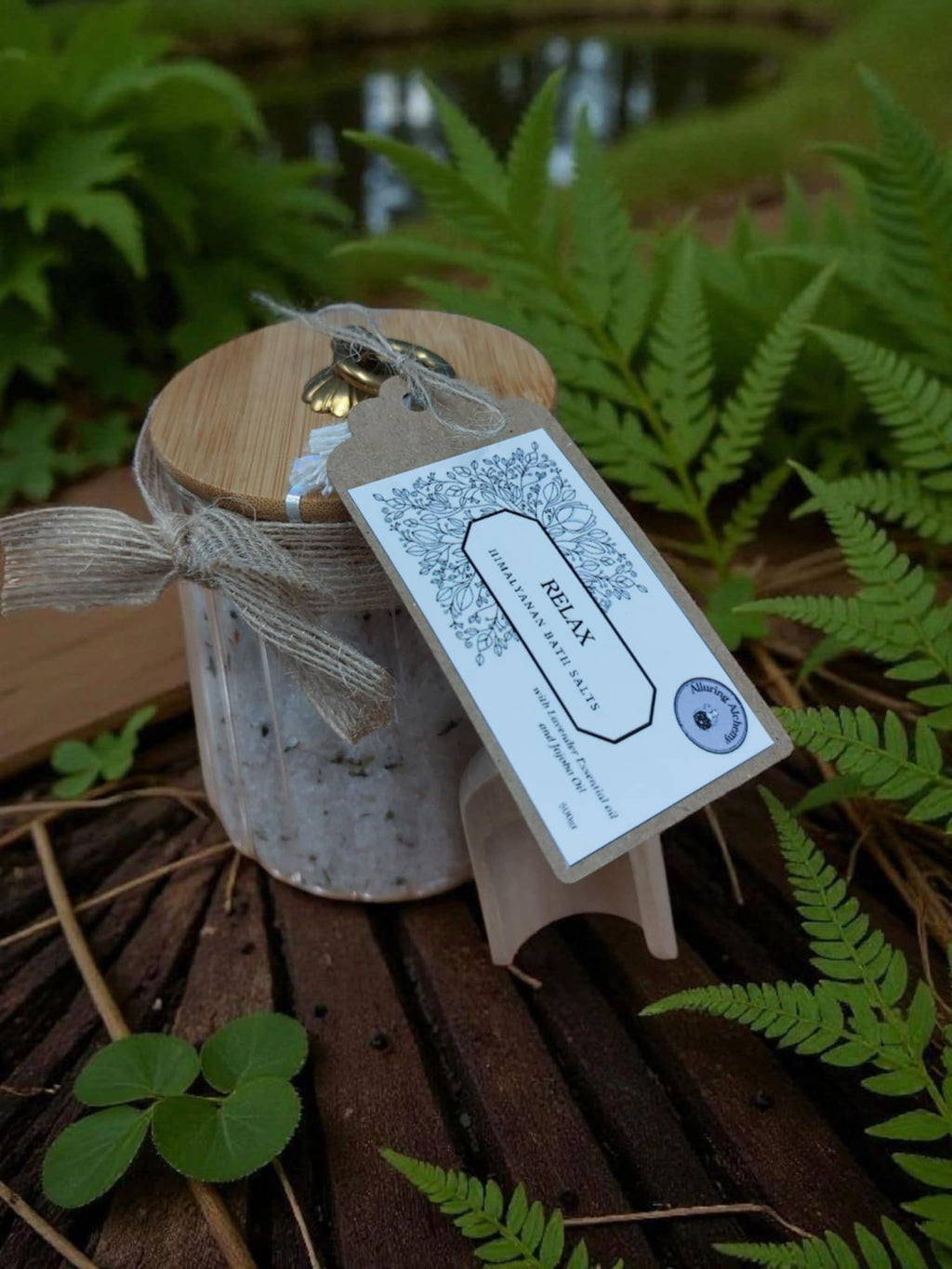 Jar with a wooden lid and decorative tag on a wooden surface with green foliage in the background