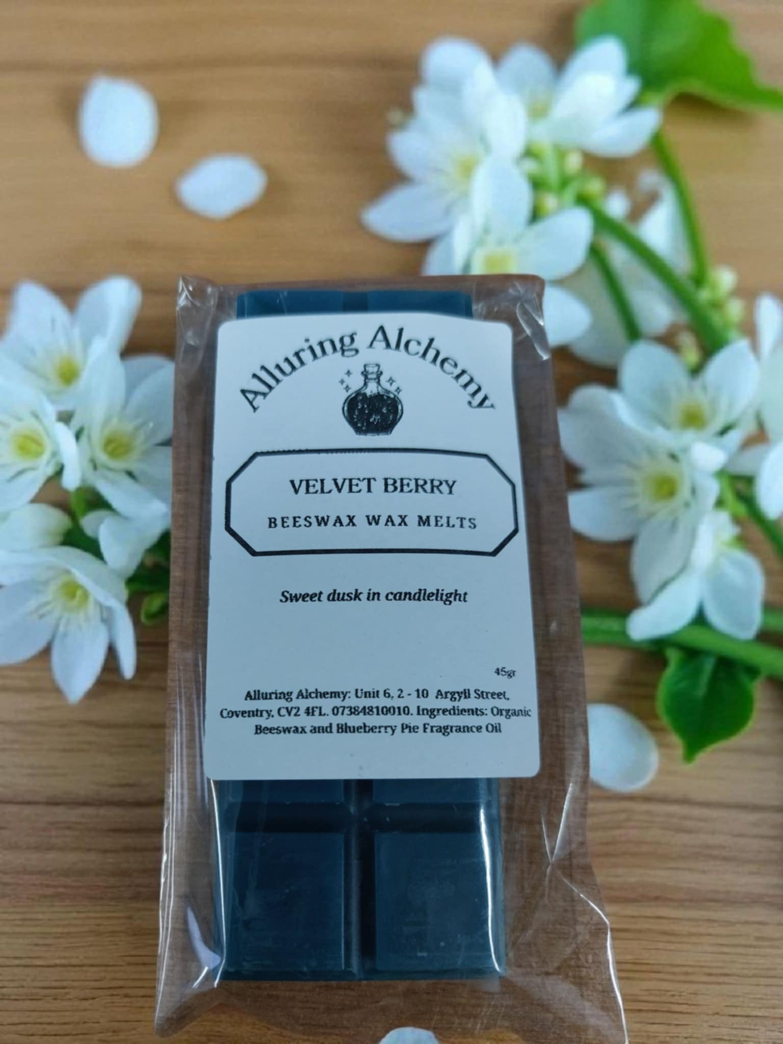 Pack of Alluring Alchemy Velvet Berry wax melts with flowers in the background