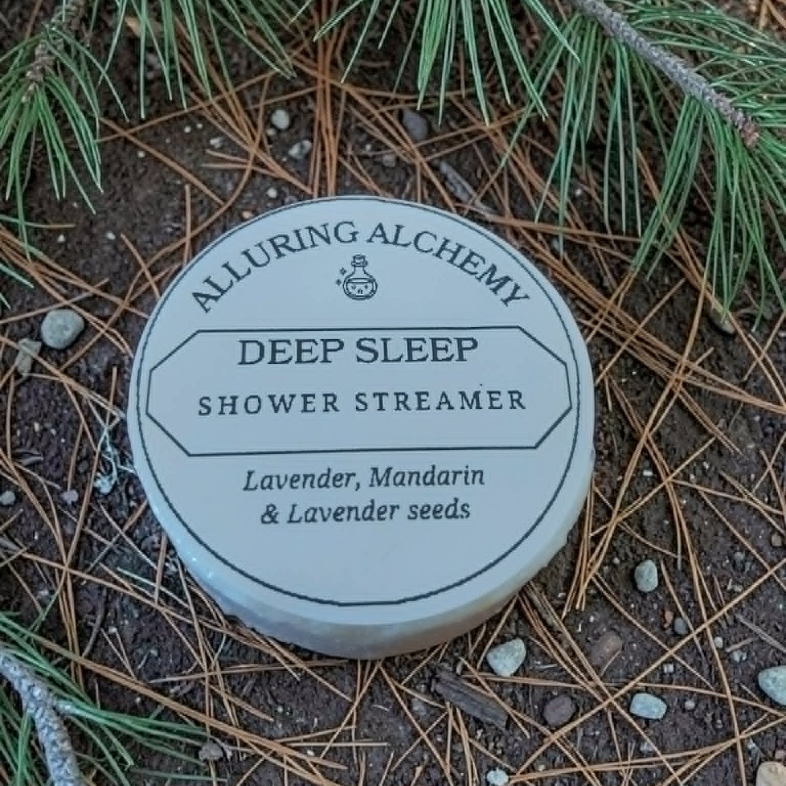 Alluring Alchemy Deep Sleep Shower Streamer on a natural background with pine needles and branches.