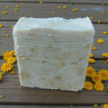 Bar of soap on a wooden surface with yellow flowers around it