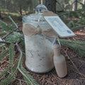 Glass jar with a crystal ball on top, surrounded by pine branches in a forest setting.