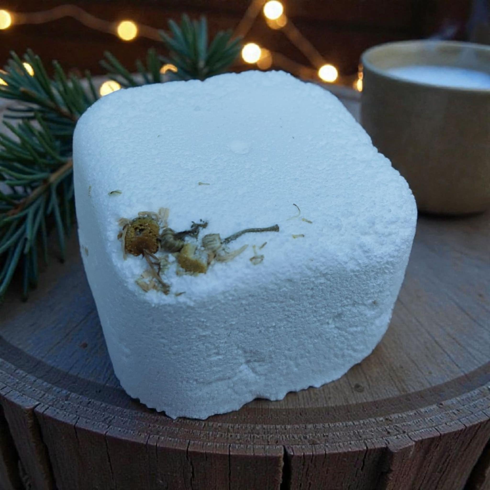 White square with chamomile petals on a log