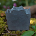 Gray stone-like object on a bed of green moss with blurred natural background