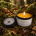 light beeswax candle in a black tin on a forest floor