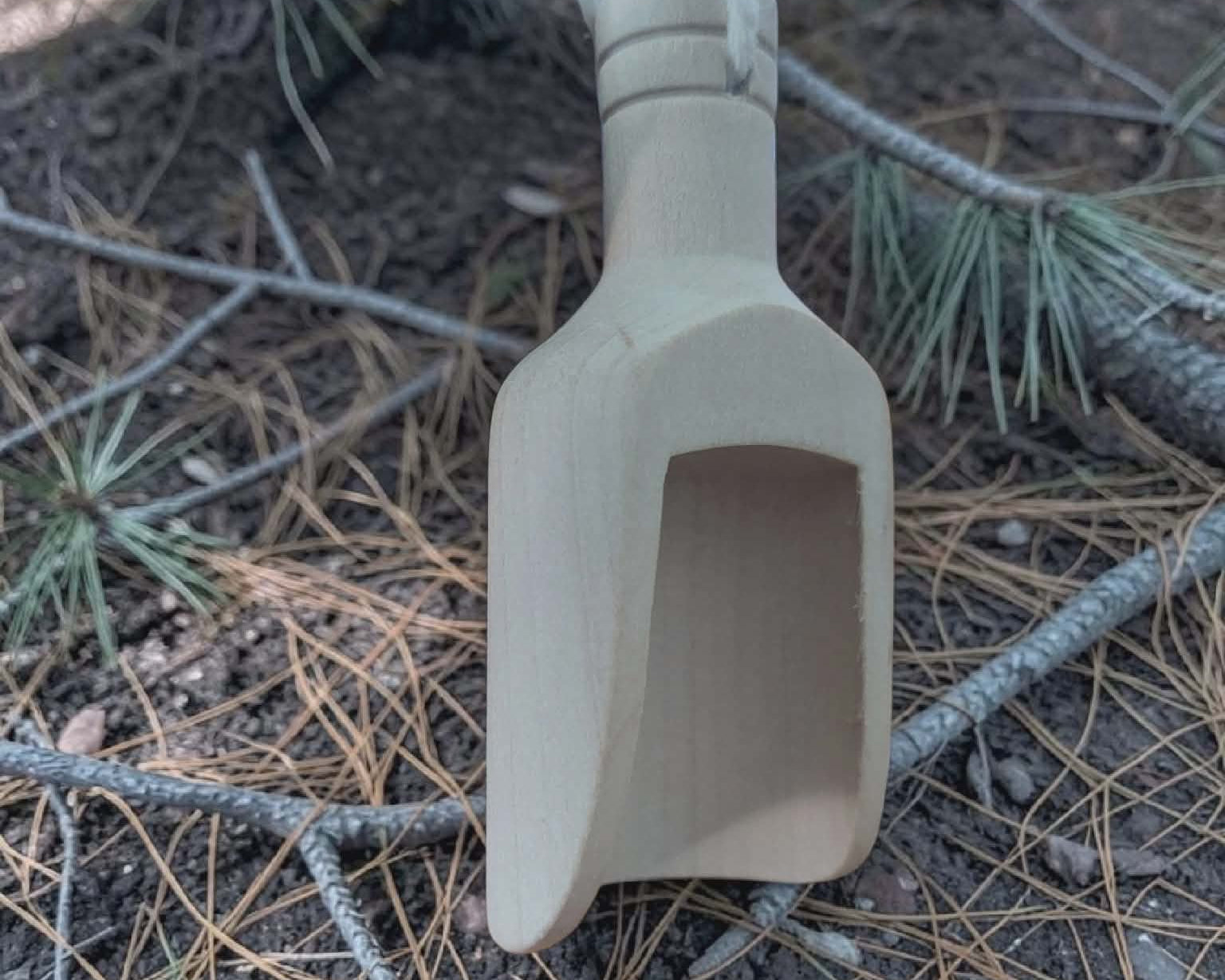 Beige scoop on a forest floor with trees and branches in the background