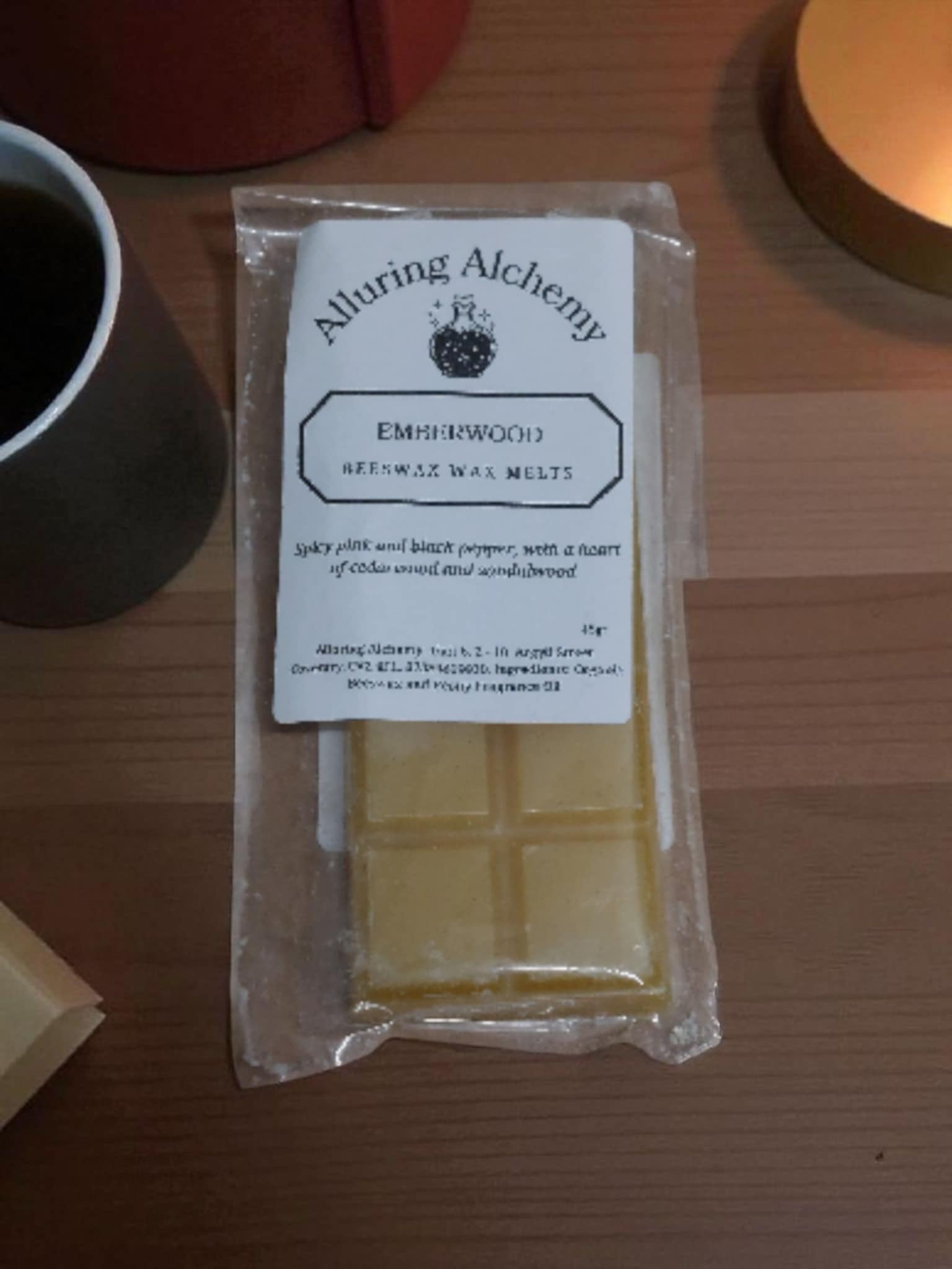 Packaged wax melts with 'Alluring Alchemy' label on a wooden surface