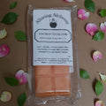 Wax melt package with 'Alluring Alchemy' branding on a decorative background with flowers and leaves.