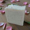 Bar of soap on a wooden surface with pink rose petals