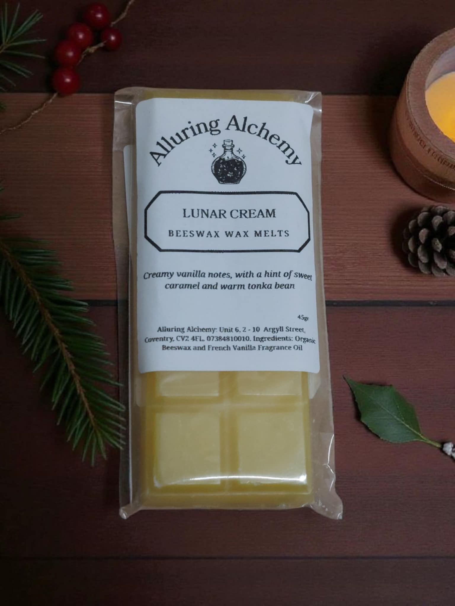 Pack of Alluring Alchemy Lunar Cream beeswax wax melts on a wooden surface with a candle and pine cone.