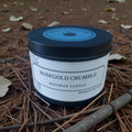 Beeswax candle labeled 'Rosegold Crumble' on a natural background with leaves and twigs.