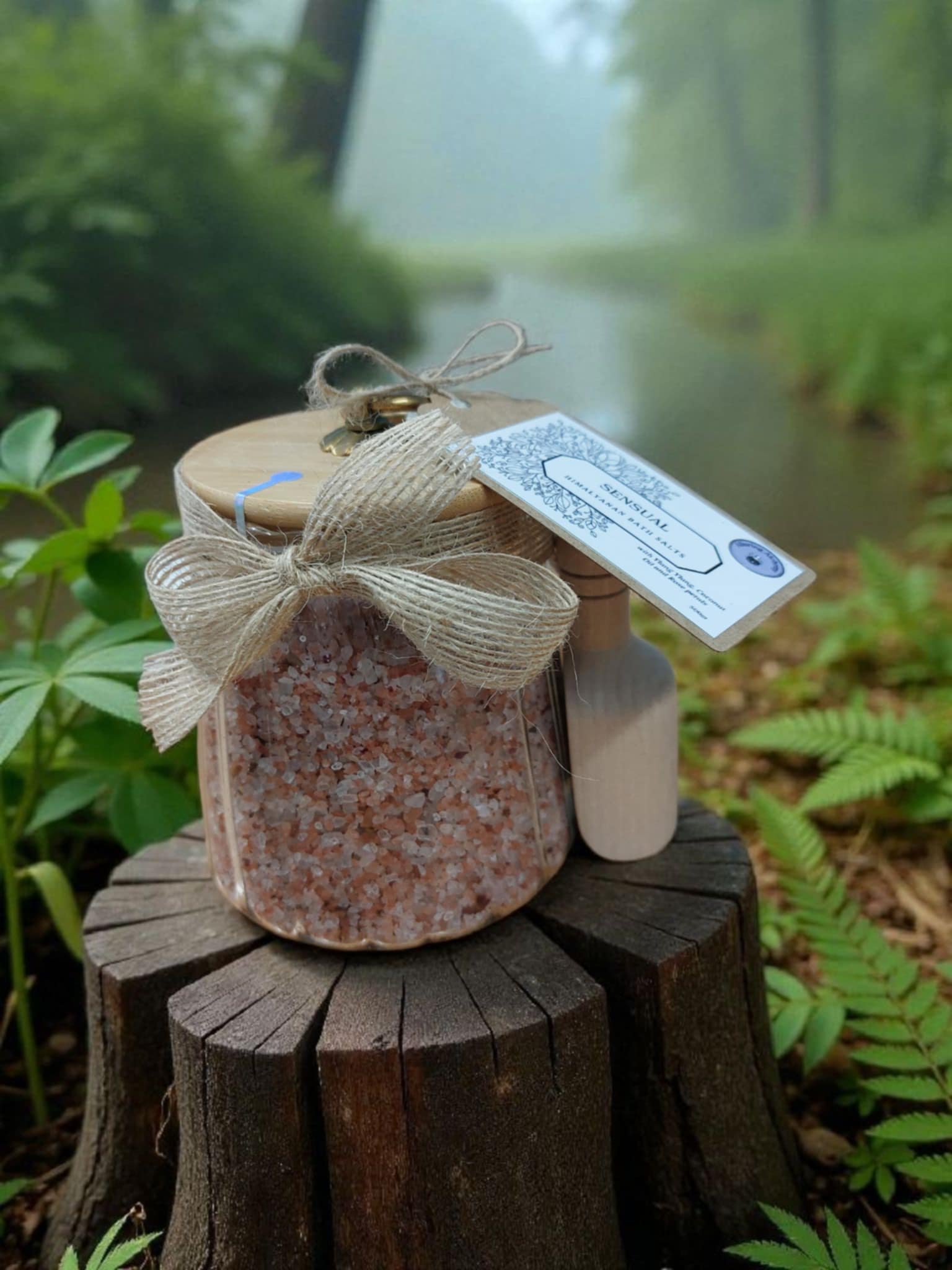 Jar of bath salts with a decorative bow and tag on a wooden stump with a natural background