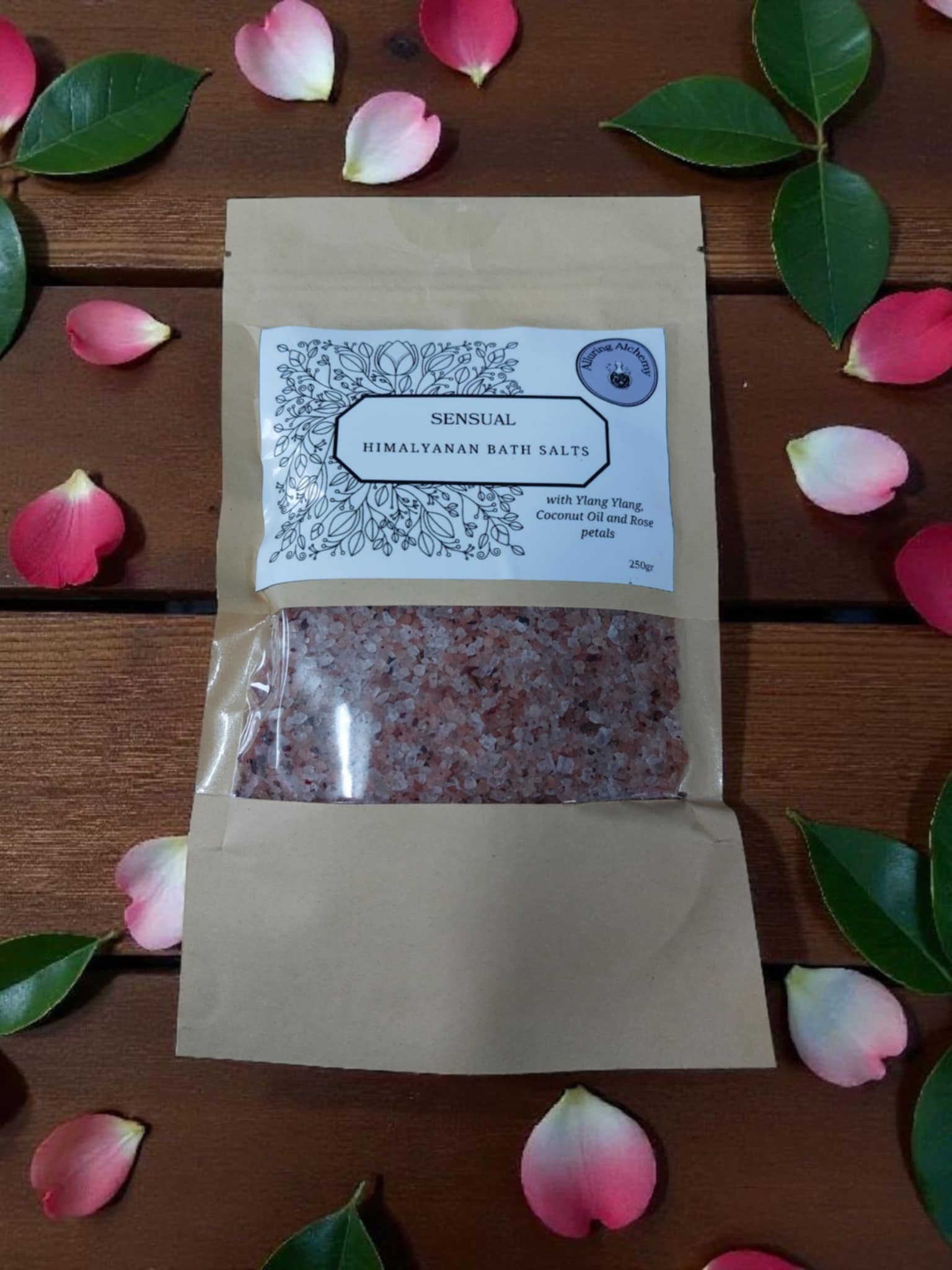 Sensual Himalayan bath salts package on a wooden surface with rose petals and leaves.