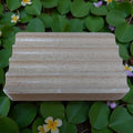 Wooden block on a green leafy background with small flowers