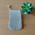 Handmade crochet soap holder on a wooden surface with a small potted succulent.