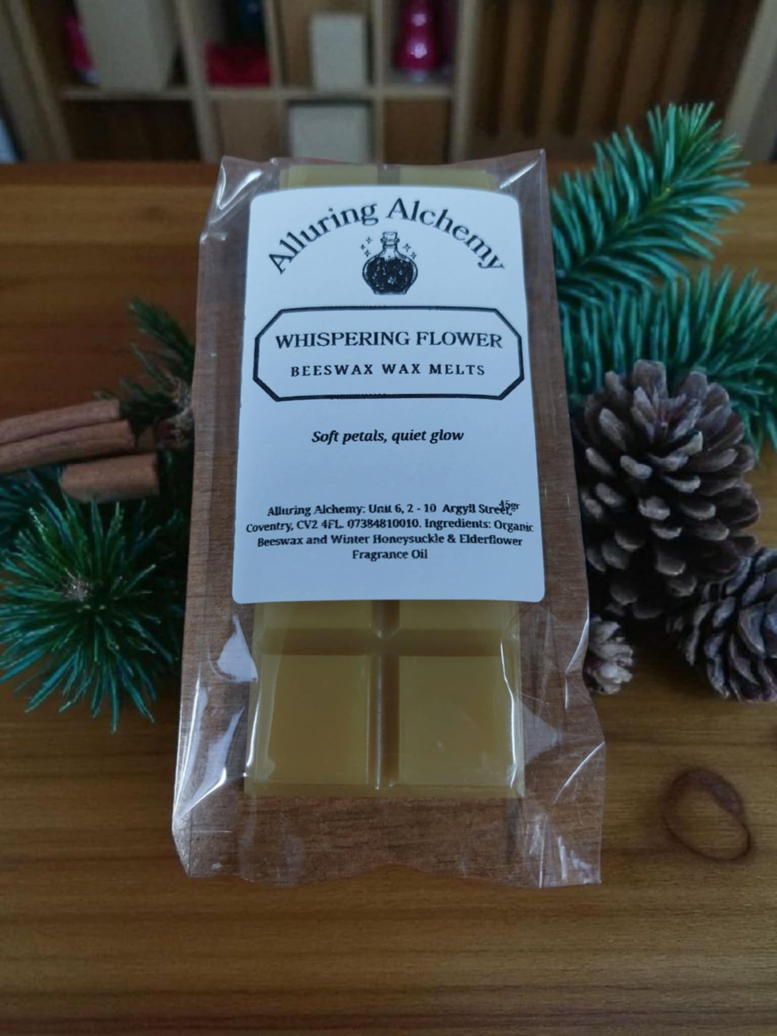 Packaged beeswax wax melts from Alluring Alchemy on a wooden surface with decorative elements.