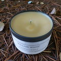 Candle in a container labeled 'Willow Whisp' on a bed of pine needles.