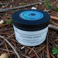Yuletide Amber beeswax candle in a jar on a natural background with pine needles and twigs.